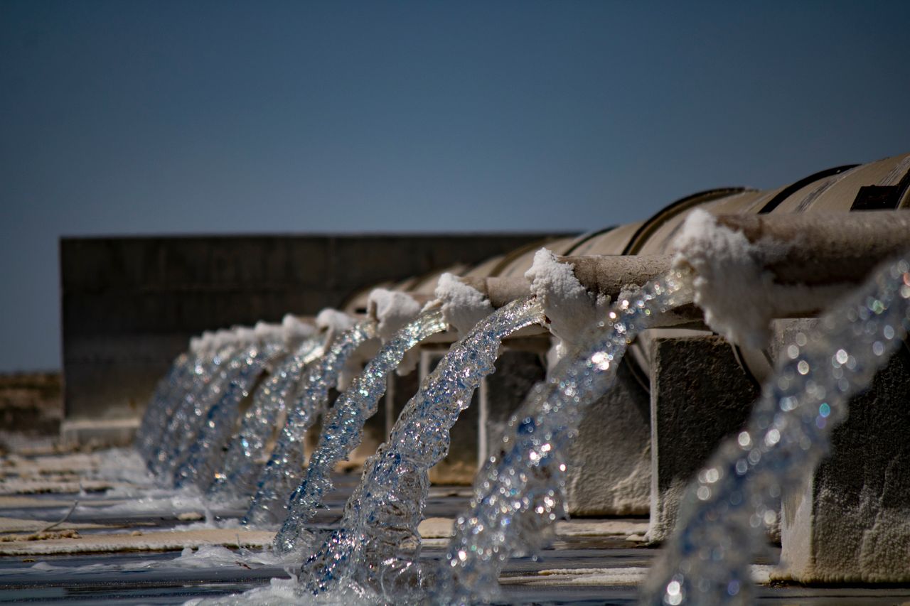 home-hero Close-up view of water flowing from industrial pipes against a clear blue sky.